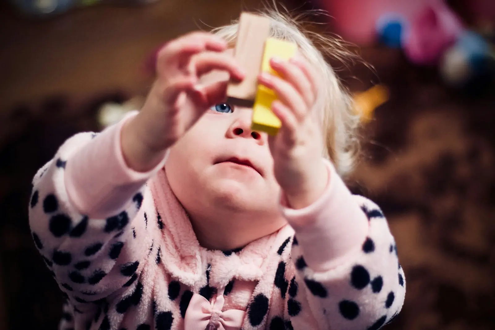 Una niña pequeña sostiene dos bloques de madera mientras juega