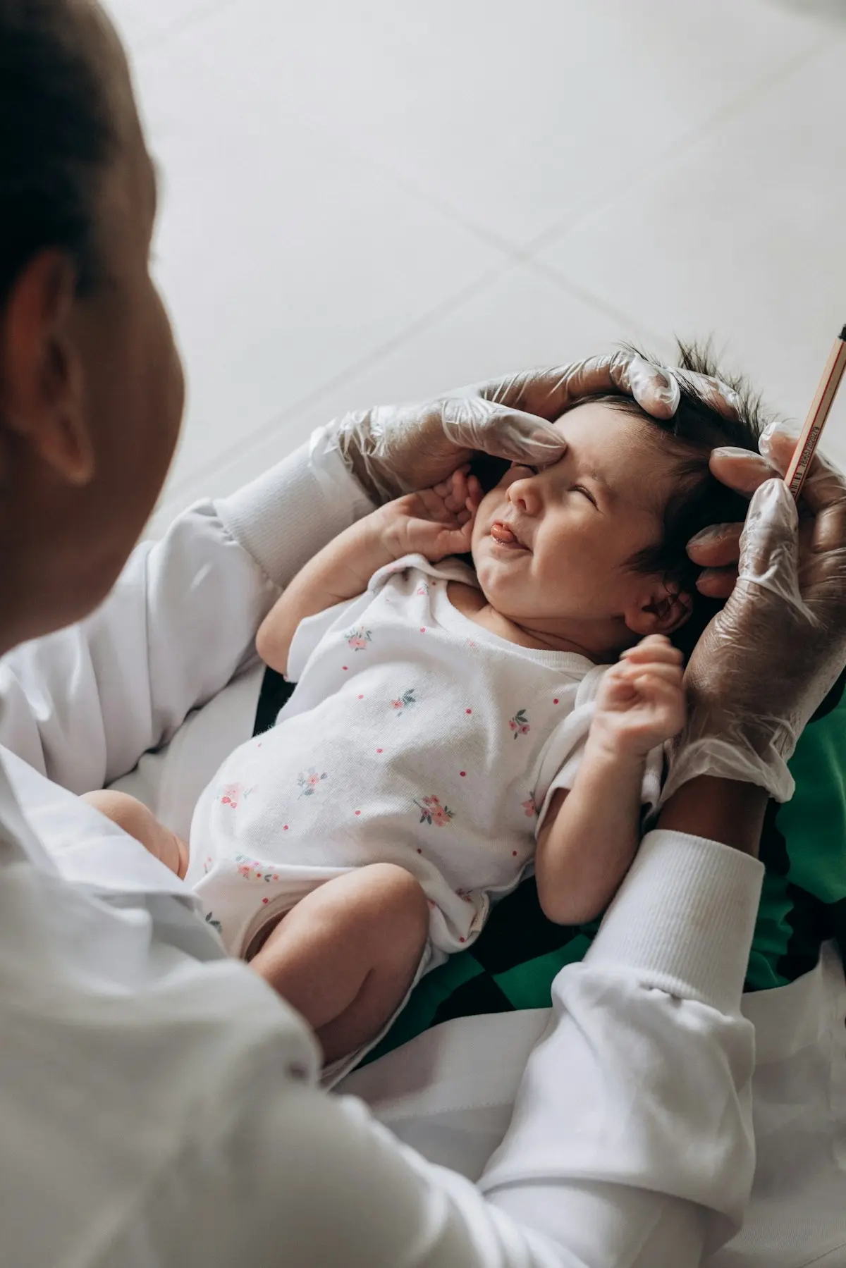 Una médica con guantes revisa los ojos de una recién nacida