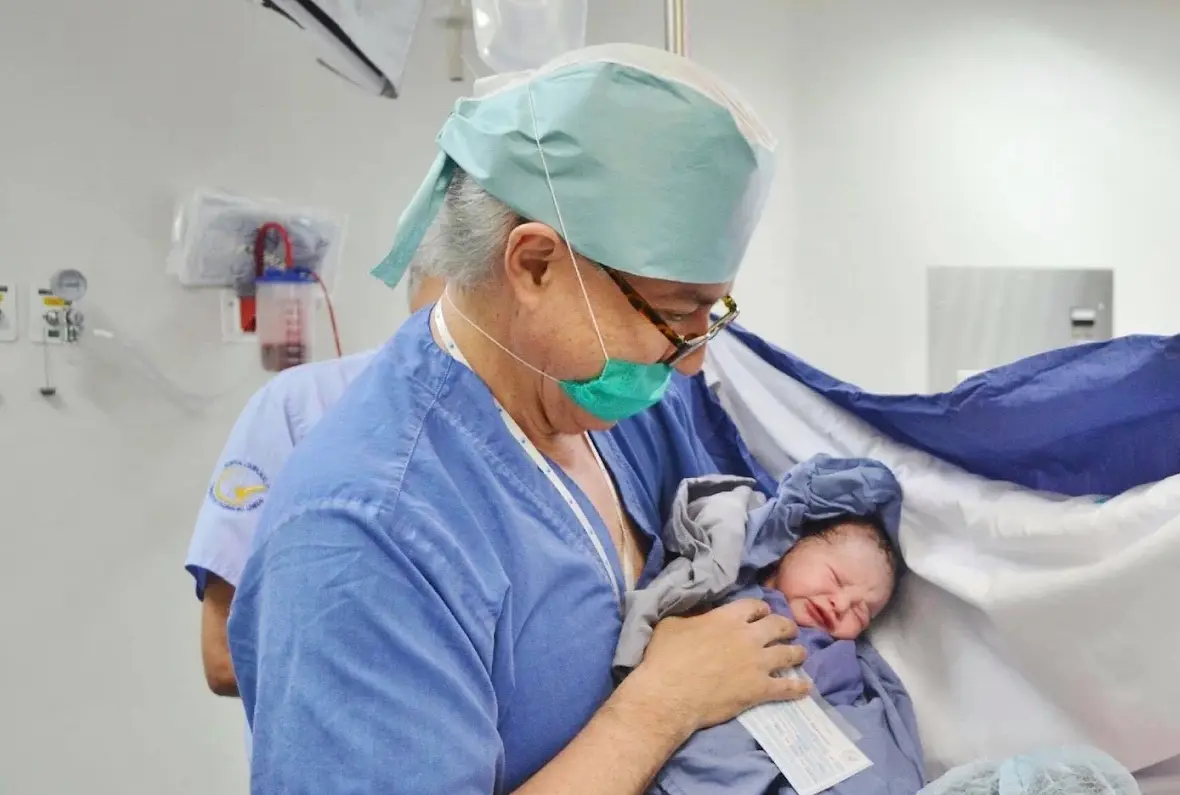 El Dr. Hashimoto sostiene a un recién nacido en la sala de partos del Hospital Fátima